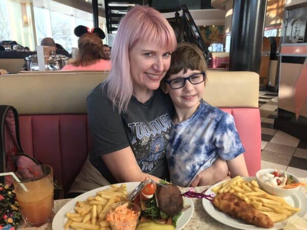 A smiling mum with her son at Annette’s Diner in Disney Village, surrounded by classic American diner vibes, enjoying a family meal after arriving at Disneyland Paris by Eurotunnel.