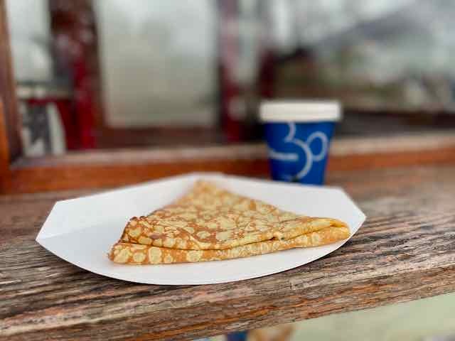 A delicious crepe on a plate and a small espresso cup