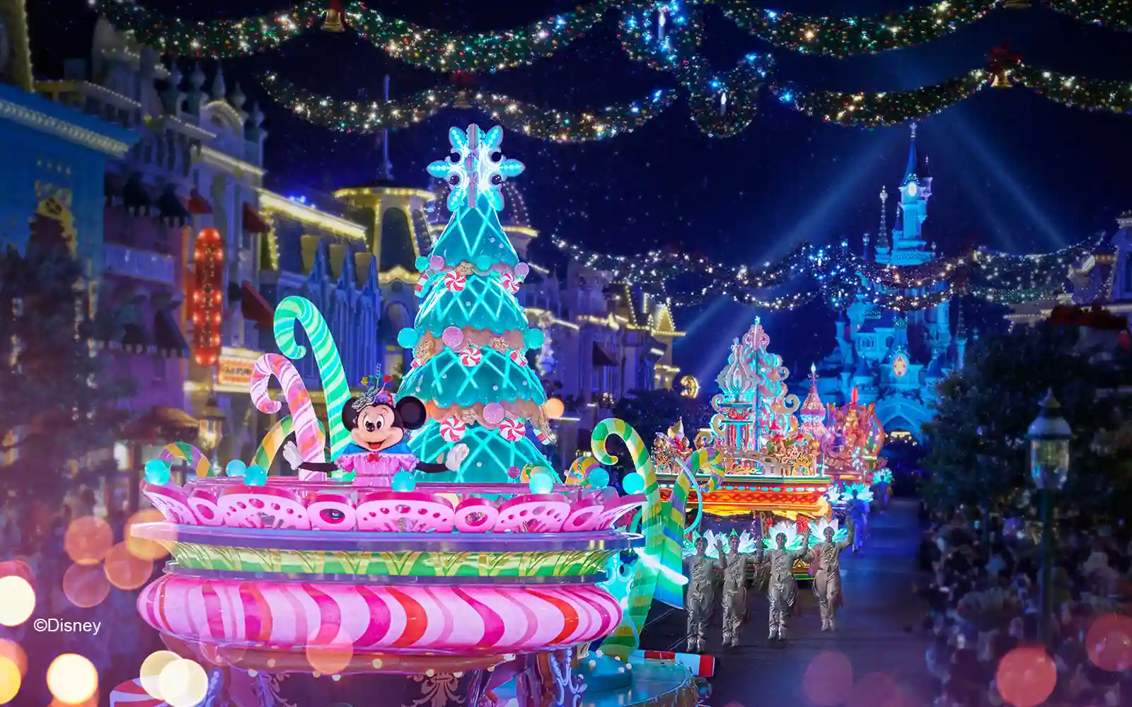 Minnie sits atop a stunningly lit parade float in candy coloured pinks and greens; a must-do in the Disneyland Paris Christmas Guide 2023