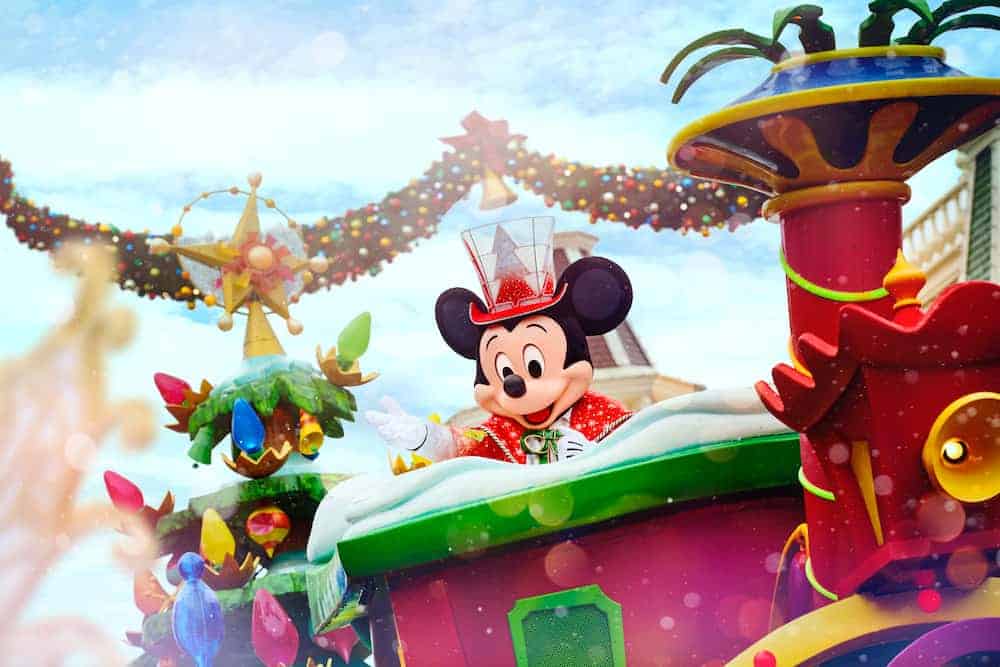 Mickey Mouse in a gorgeous red suit and fun top hat is driving a jewel-coloured Christmas train, complete with a brightly green tree