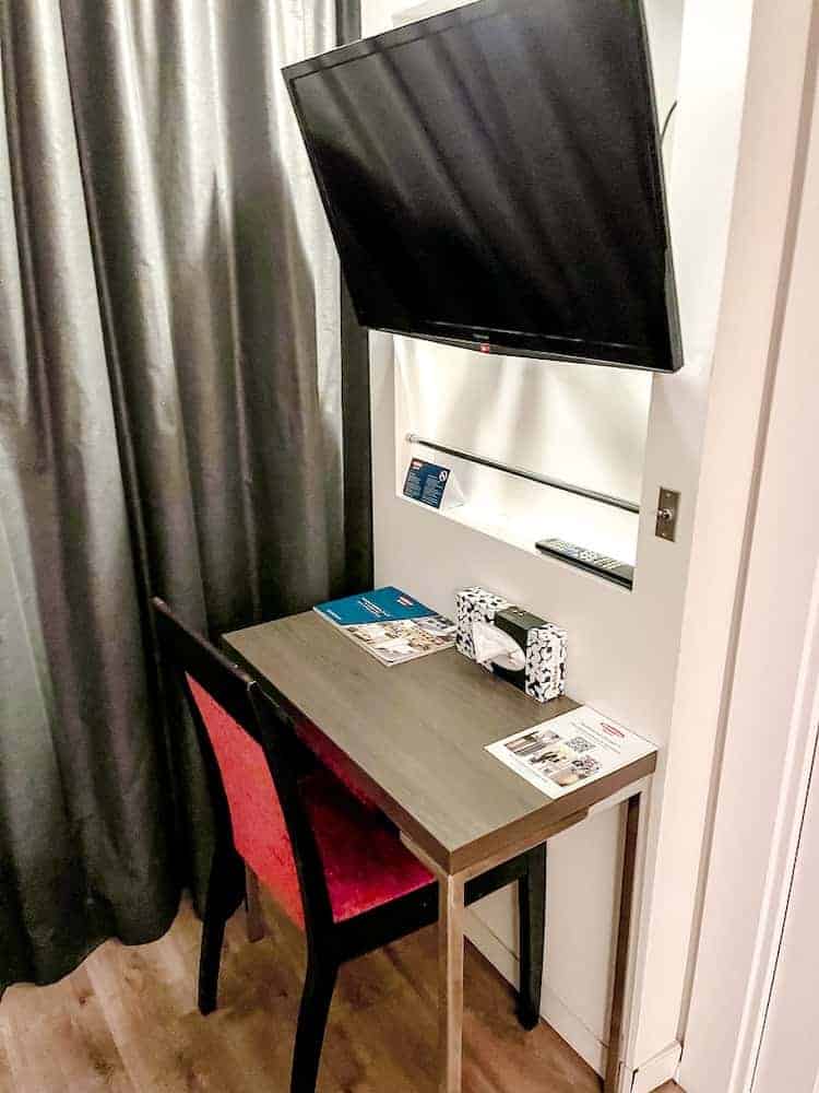 A smart desk and red chair sit beneath a flatscreen TV at this 4-star hotel