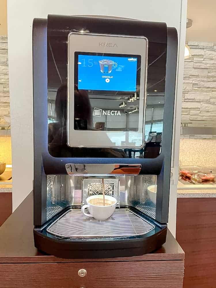 A modern hot drinks machine with digital display. A cup is being filled with lovely hot chocolate