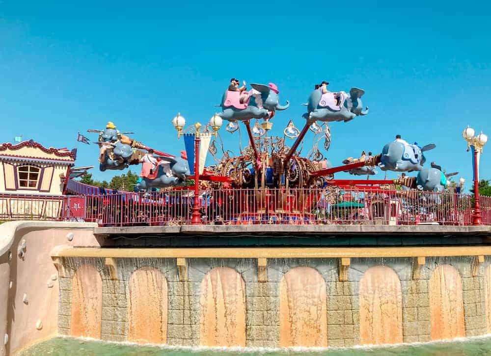 Dumbo the Flying Elephant attraction carrying happy children and their smiling parents on a blue sky day