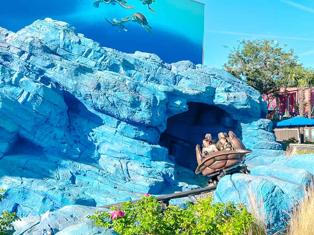 Crush's Coaster attraction - a turtle shell-shaped rollercoaster zooms out of a blue coral reef; an essential ride when making your own Disneyland Paris itinerary 