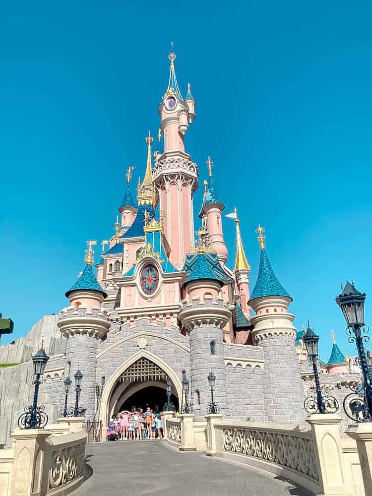 Under a bright blue sky sits Le Chateau de la Belle au Bois Dormant - Sleeping Beauty Castle in Disneyland Paris