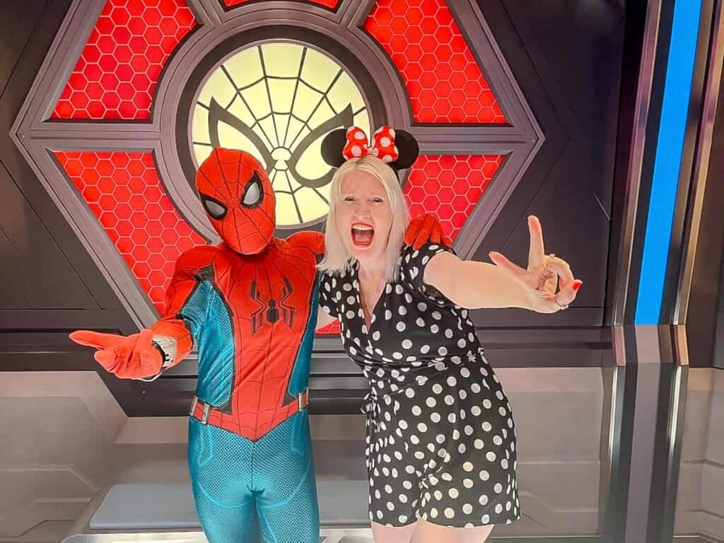 What questions to ask Disney Characters? These character meet started with asking Spider-Man what bad guys he's seen in Avengers Campus. Here Spider-Man and a blonde woman in a polka dot outfit pose with their arms outstretched.