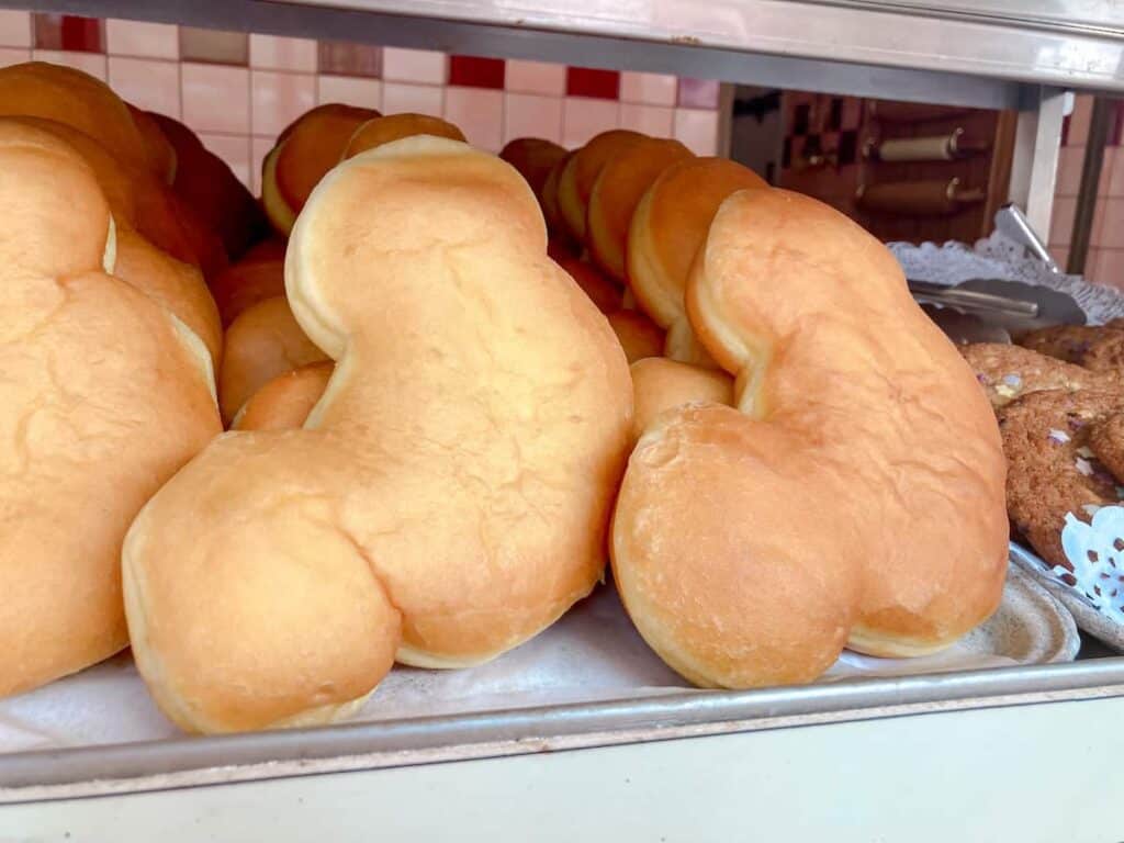 A tray of golden Mickey-shaped beignets are stacked on a tray