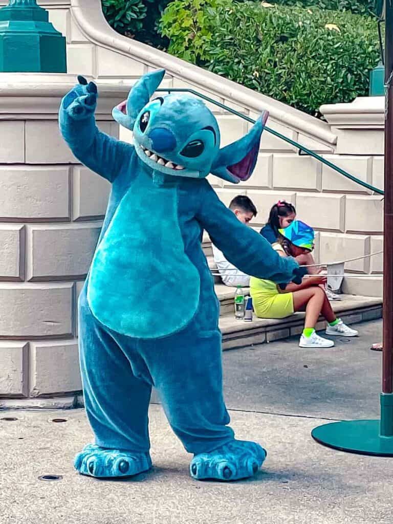 The loveable Stitch poses playfully. Children nearby have just enjoyed their character interaction at Disneyland Paris