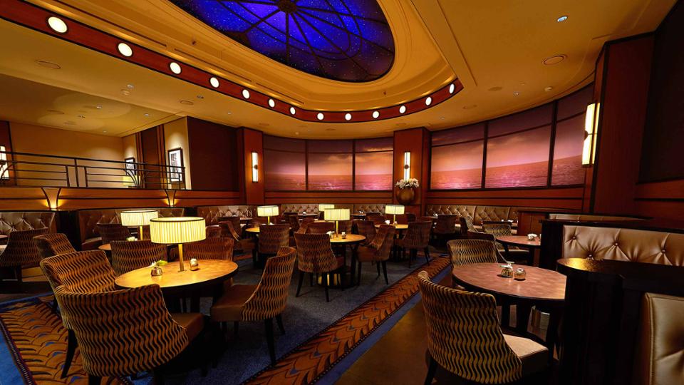 The Compass Club Lounge at Disney Newport Bay Club evokes a maritime feeling. Mahogony wood furniture and patterned navy and burgundy carpet make the plush lounge even more inviting to hotel guests.