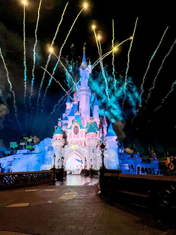 Sleeping Beauty Castle glows with projections and fireworks shoot overhead. The scene is magical.