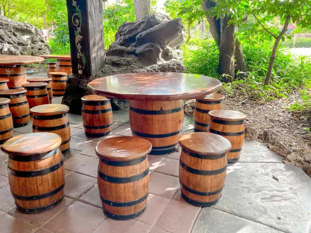 A large seating area in Adventureland has barrels for seating and large, welcoming wooden table tops to accommodate families eating their own food