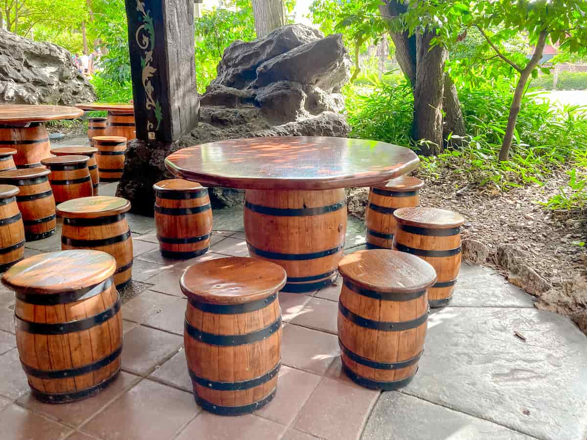 A large seating area in Adventureland has barrels for seating and large, welcoming wooden table tops to accommodate families eating their own food