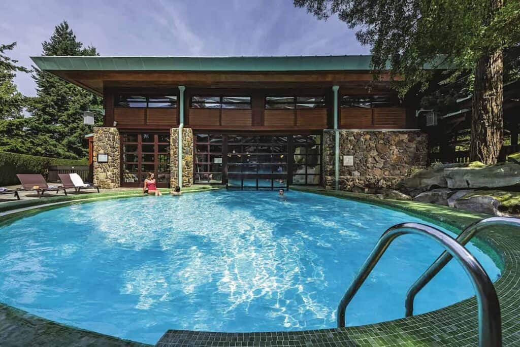 The Disney Sequoia Lodge pool is shimmering in blue as a hotel guest relaxes. The tranquil setting lends its rating as one of the best hotels at disneyland paris.
