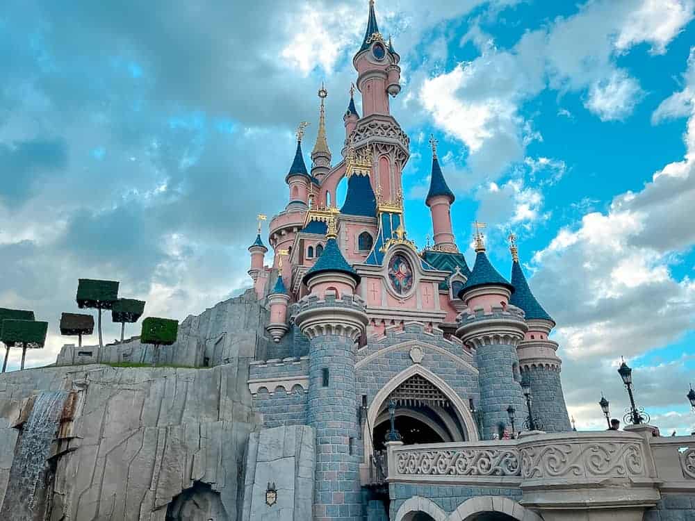 Sleeping Beauty Castle on a puffy cloud day looking picturesque without the crowds during Extra Magic Time at Disneyland Paris.