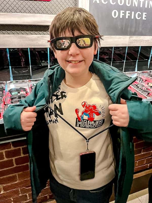 An 11 year old boy in a Spider-Man jumper is wearing 3D glasses as he is about to board Spider-Man W.E.B. Adventure in Disneyland Paris. He is grinning with excitement
