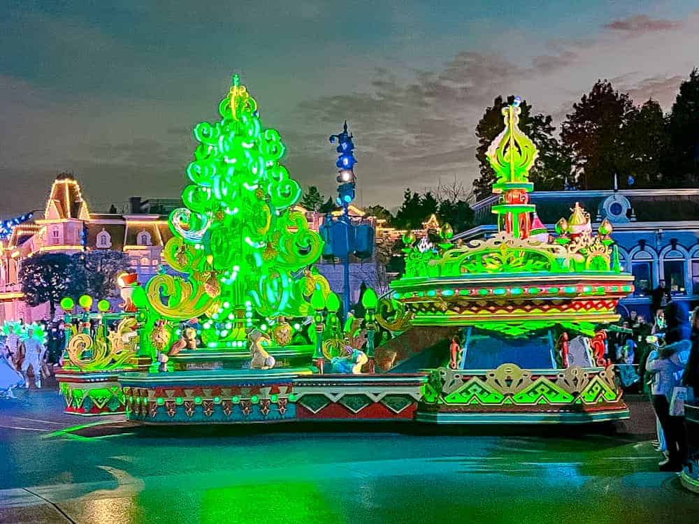 The iconic Christmas tree float aglow in green during Mickey’s Dazzling Christmas Parade, a must-see highlight of the Disneyland Paris holiday season.