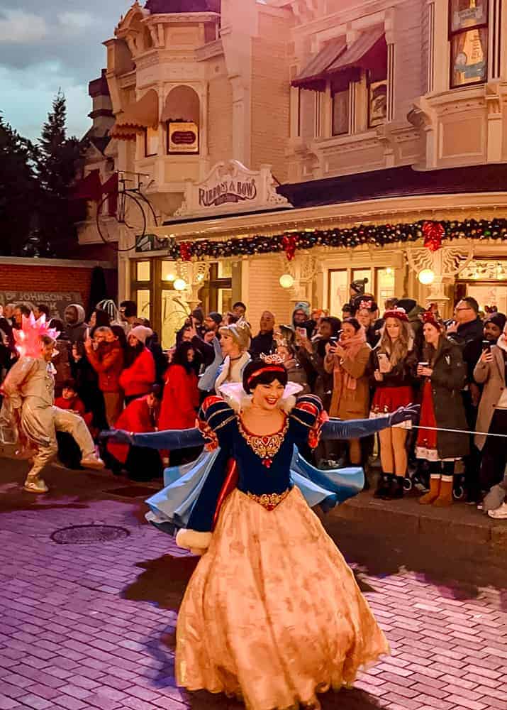 Snow White glides through Town Square during Mickey’s Dazzling Christmas Parade, creating a magical moment for those enjoying the free viewing areas.