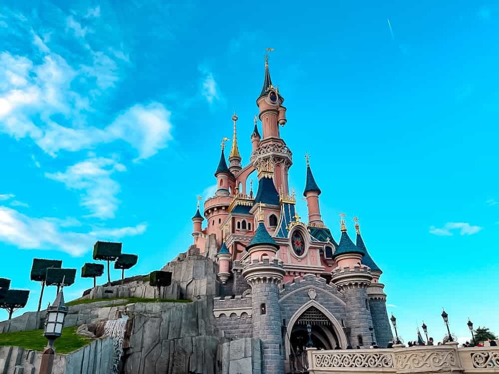 Sleeping Beauty Castle glowing under a bright blue sky at Disneyland Paris, showcasing the stunning architecture that makes the park magical. A must-see for anyone hoping to explore the park despite Disneyland Paris Dynamic Ticket Pricing options.