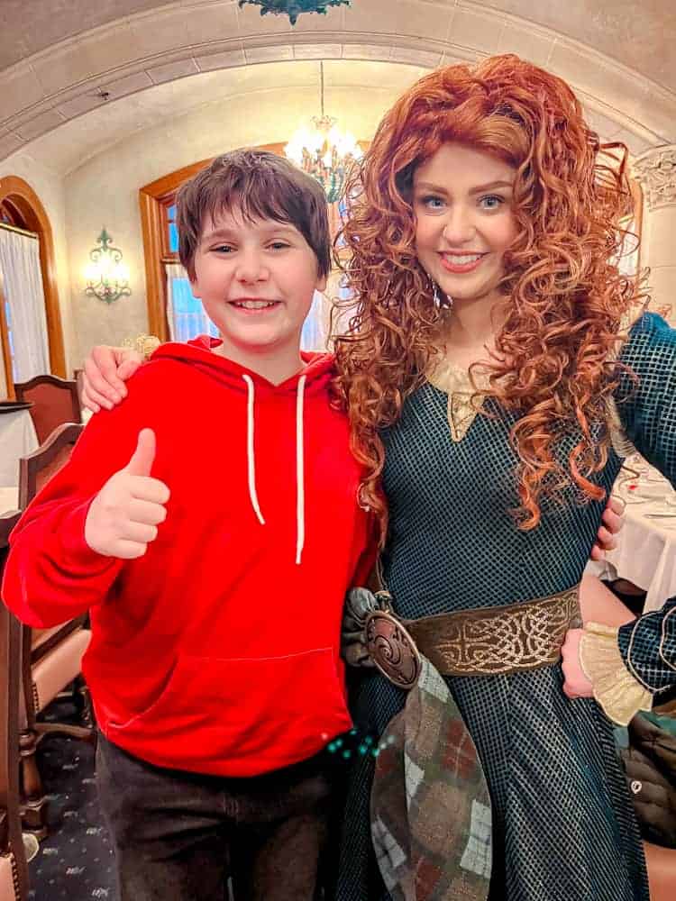 Merida and a young guest smile together inside Auberge de Cendrillon during the Disneyland Paris Princess Breakfast.