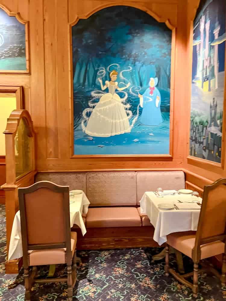 A cosy dining nook at Auberge de Cendrillon, decorated with an enchanting mural of Cinderella and her Fairy Godmother.