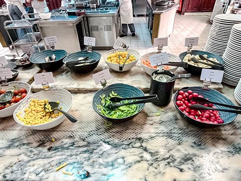 Fresh salad bar at Plaza Gardens Disneyland Paris, featuring cucumbers, corn, radishes, and other toppings