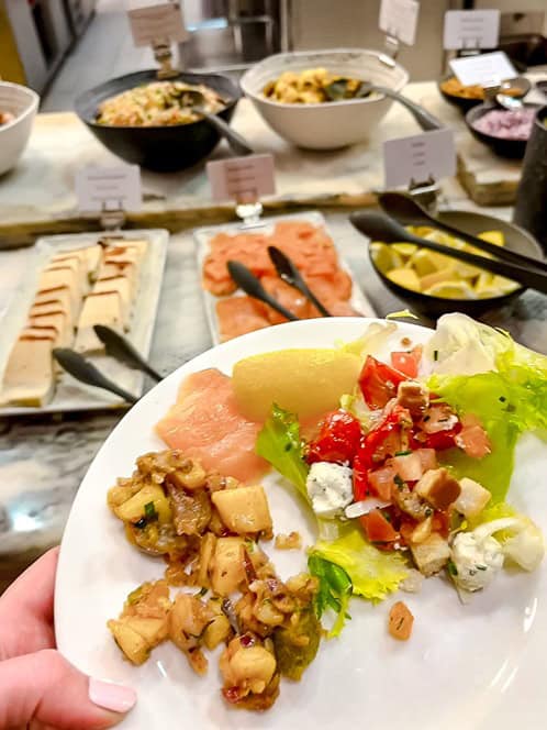 A plate filled with fresh salad, smoked salmon, and warm dishes from Plaza Gardens Disneyland Paris buffet.