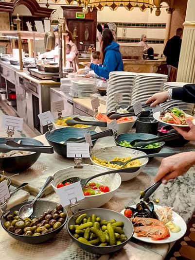 Fresh salad bar at Plaza Gardens Disneyland Paris, offering a variety of toppings, olives, and pickles.