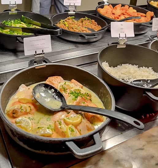 Buffet selection at Disneyland Paris Plaza Gardens dinner featuring salmon in lemon sauce, rice, and fresh vegetables.
