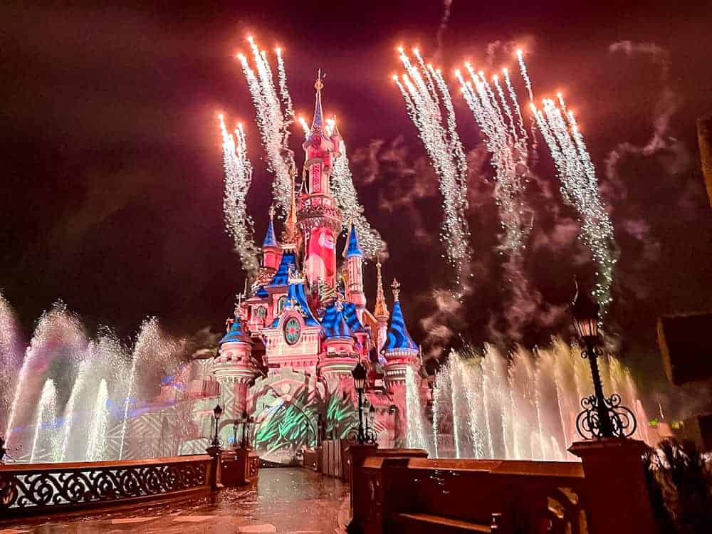 Sleeping Beauty Castle at Disneyland Paris illuminated by fireworks and fountains at night. Discover Disneyland Paris advice on the best places to watch the fireworks.
