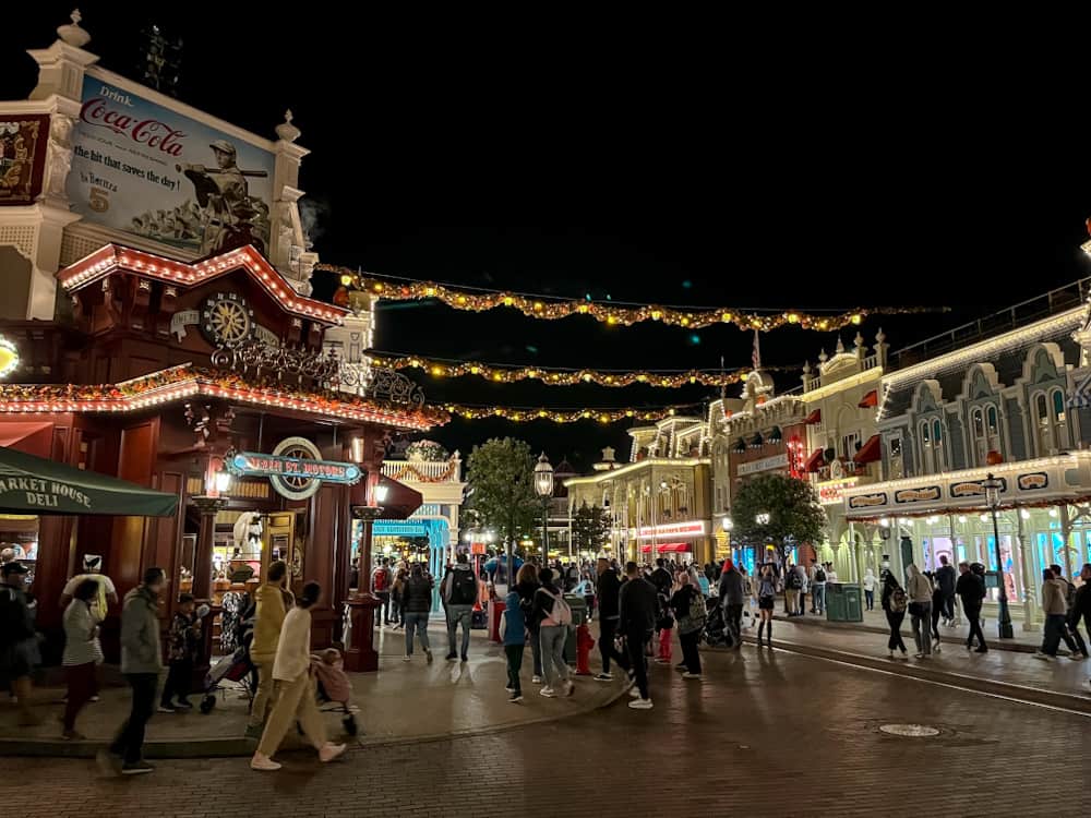 Crowds gathering on Main Street at Disneyland Paris under glowing garlands — a lively location for catching the best Disneyland Paris fireworks spot.