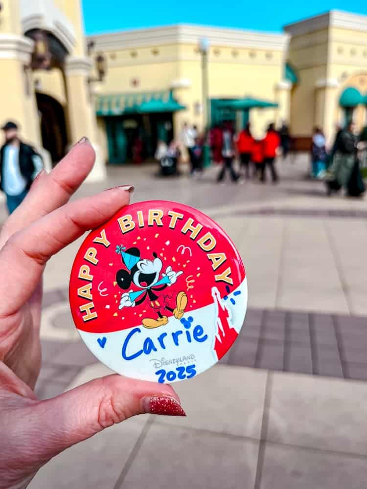 Disneyland Paris birthday badge held up in front of the Walt Disney Studios Park entrance