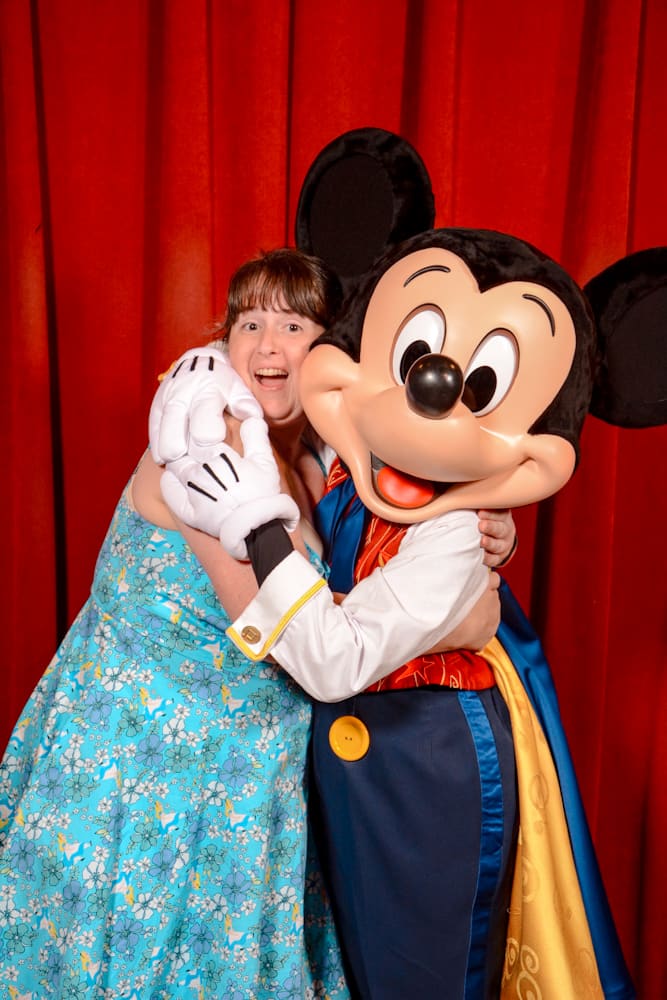 Guest hugging Mickey Mouse inside the Meet Mickey theatre, now part of the Disneyland Paris Virtual Queue system.