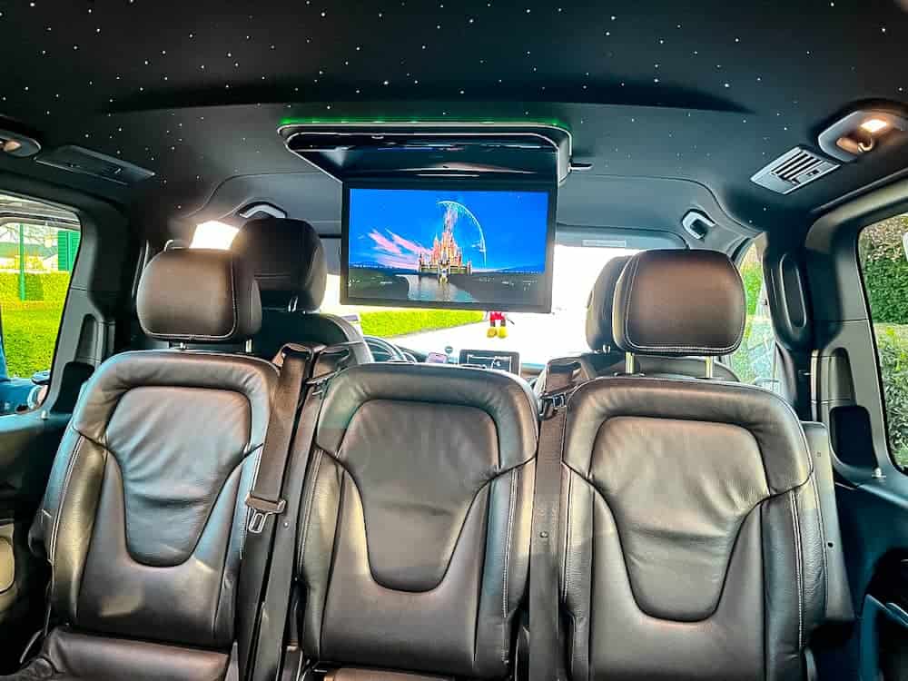 Interior of private transfer van with Disney castle movie intro playing, part of a Disneyland Paris one day itinerary