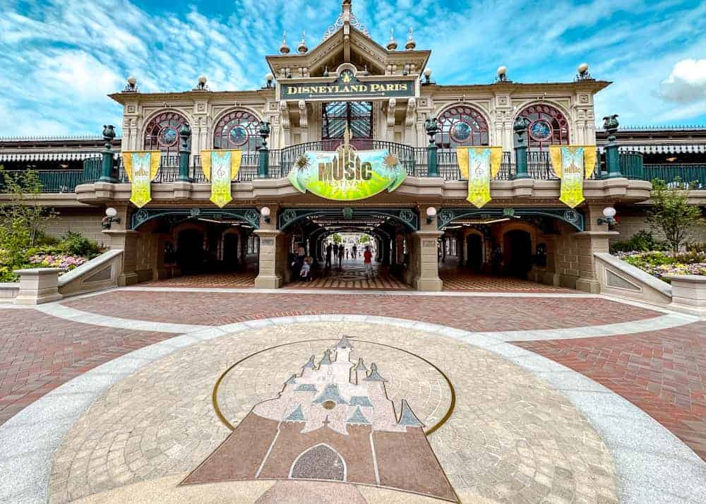 The entrance to Disneyland Paris dressed for the Disney Music Festival, featuring banners, pastel colours, and the castle crest. A picture-perfect welcome.