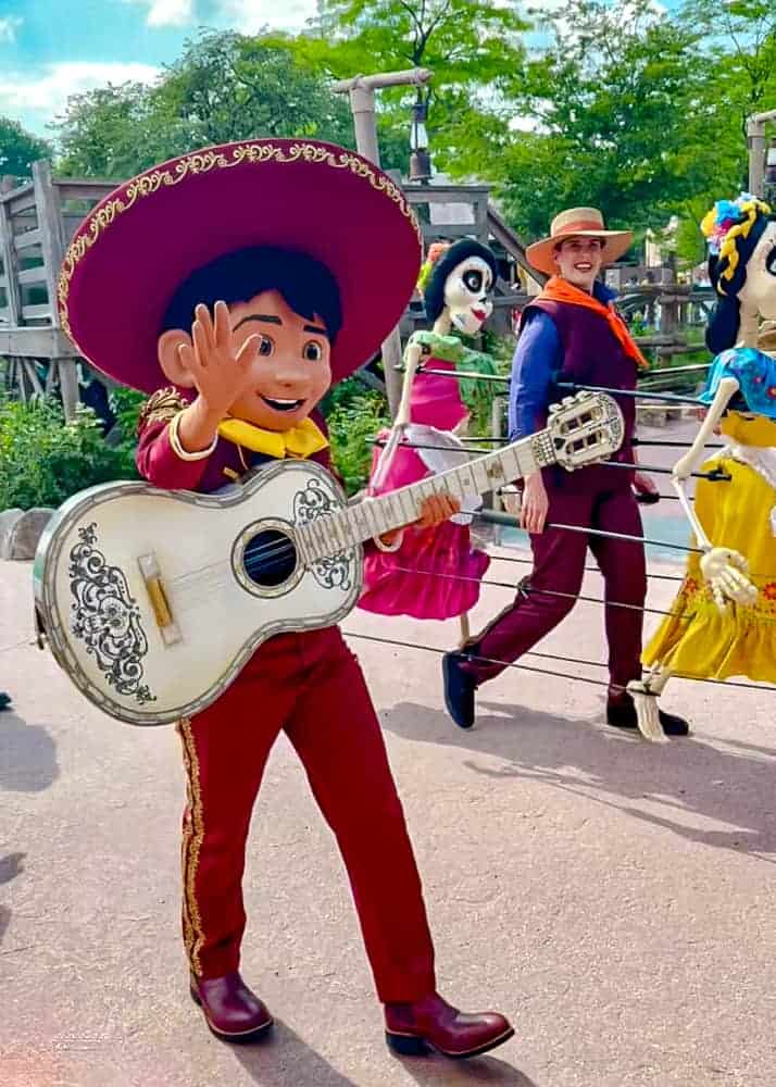 Miguel from Coco waves to the crowd while playing guitar during the Disney Music Festival parade at Disneyland Paris. A lively fan-favourite.