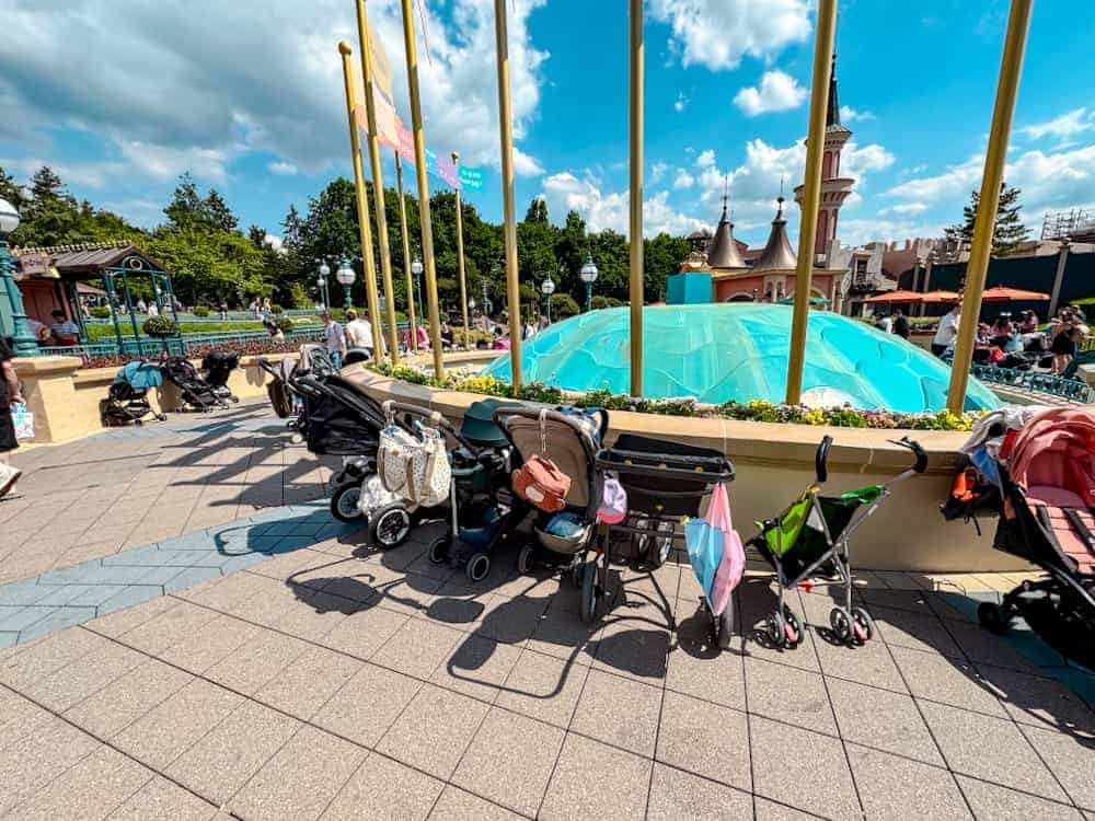 Pushchairs parked around the colourful fountain near the attraction ‘It’s a Small World’ at Disneyland Paris, waiting during a sunny day.