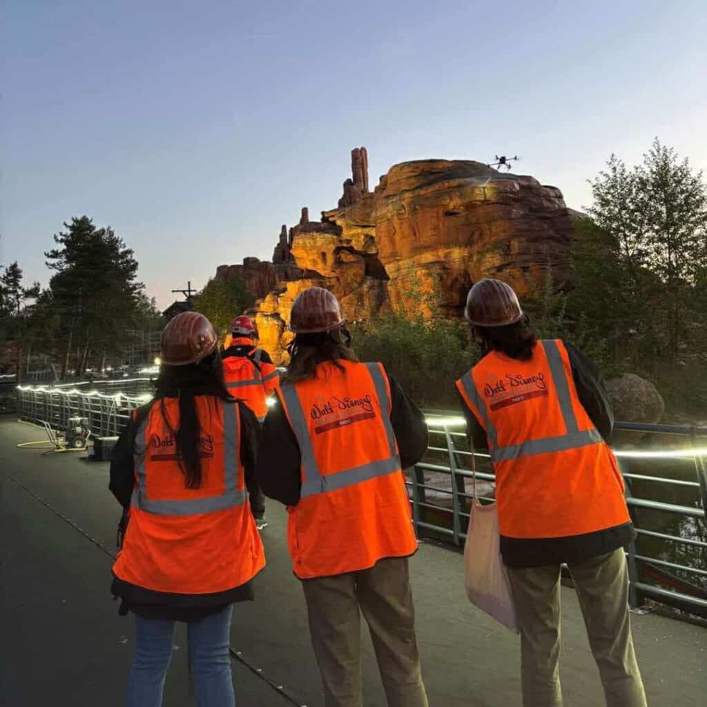 Disneyland Paris Imagineering team in orange vests overlooking Big Thunder Mountain during twilight restoration work