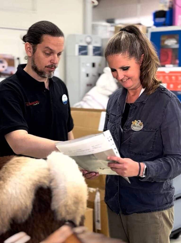 Disneyland Paris Cast Members reviewing refurbishment documents, with the goat animatronic’s fuzzy backside visible in the foreground