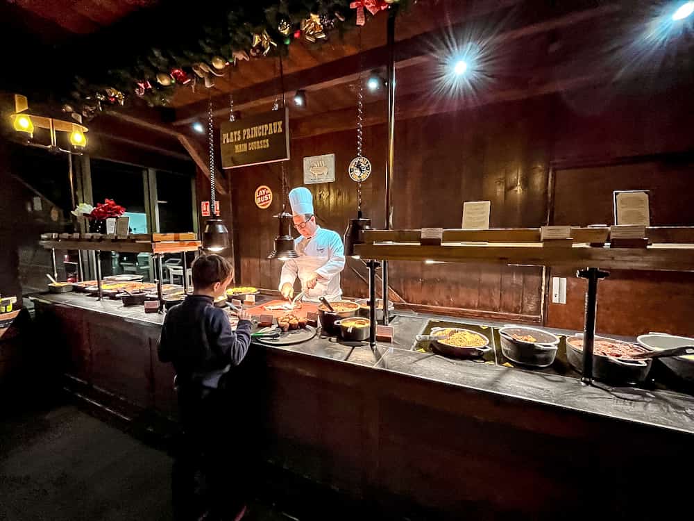 A chef slicing meat at the carving station inside Billy Bob’s La Grange at Disneyland Paris while a child looks on.