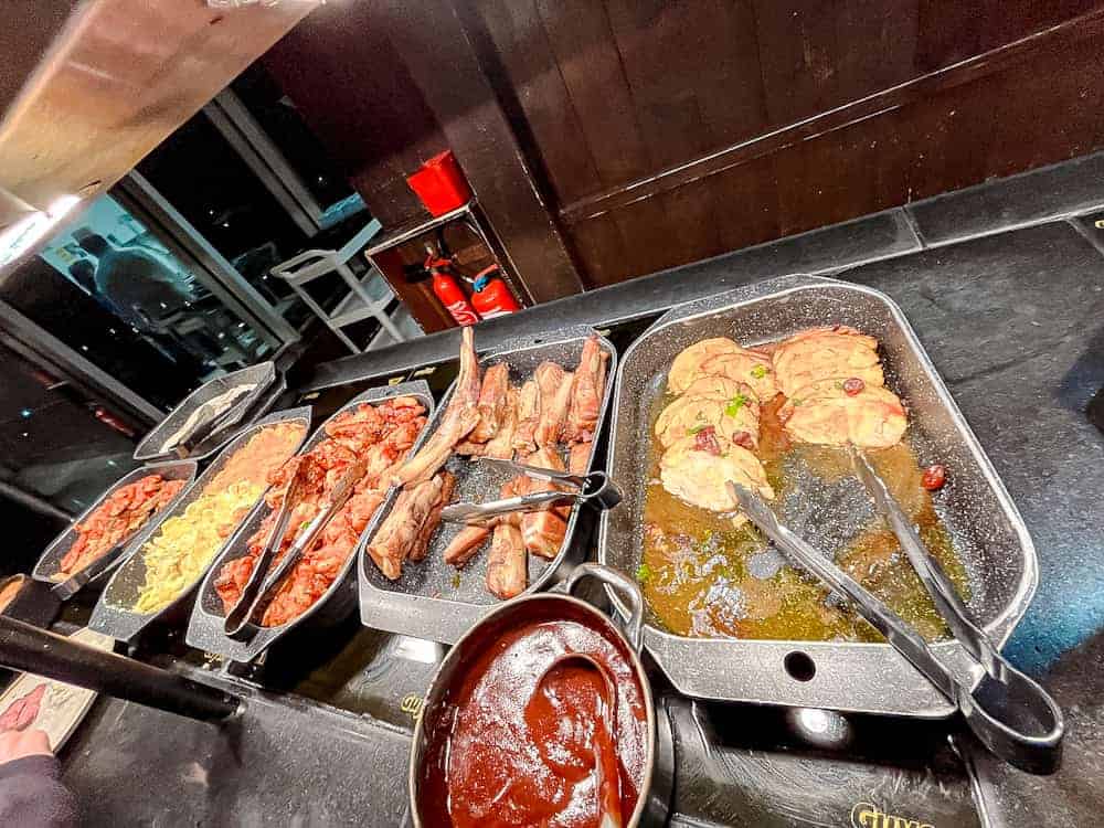 Grilled sausages, ribs, and barbecue chicken displayed at the Tex-Mex hot food station at Billy Bob’s La Grange buffet.