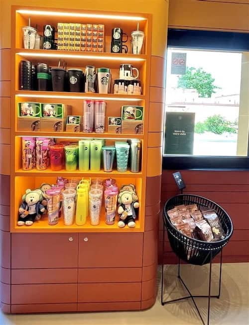 Colourful display of Starbucks merchandise including mugs, tumblers, bears and snacks inside the newly reopened Starbucks at Disneyland Paris Santa Fe Hotel.