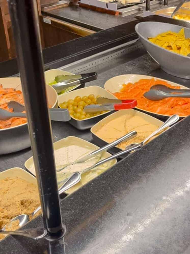 A selection of cold starters including smoked salmon, green grapes, tortilla chips, and assorted hummus-style dips at Billy Bob’s La Grange buffet.