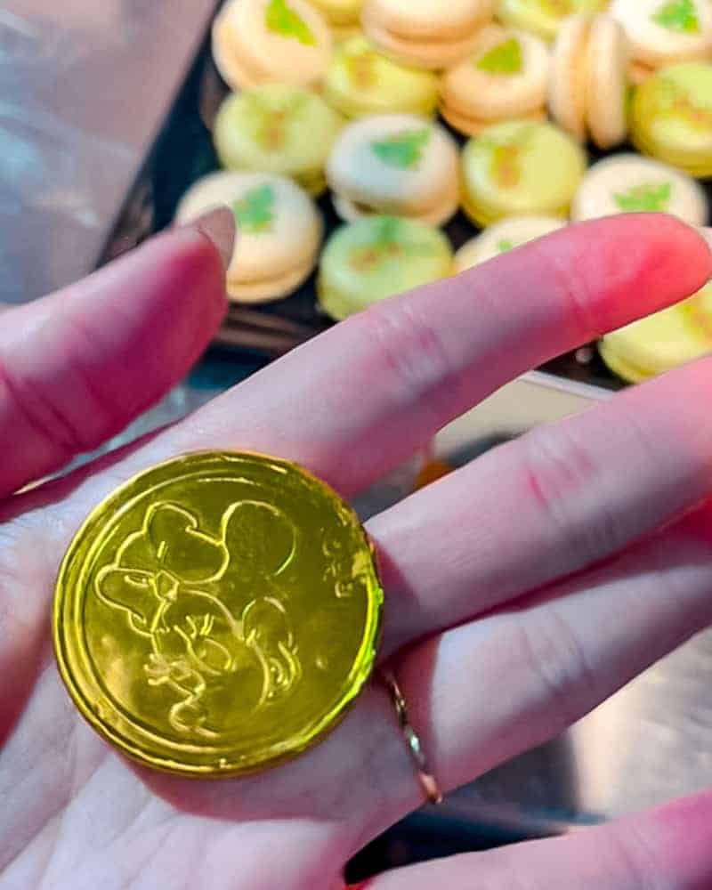 A hand holding a shiny golden chocolate coin with Minnie on the front, available at Billy Bob’s buffet.