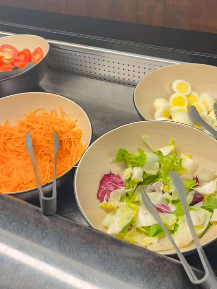 Bowls of fresh salad ingredients including lettuce, shredded carrots, sliced tomatoes, and hard-boiled eggs at the buffet in Billy Bob’s La Grange.