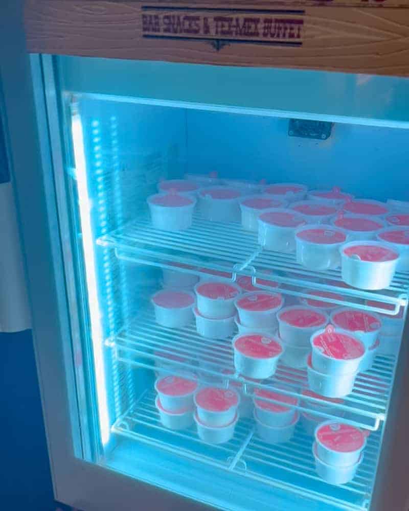 A lit-up fridge filled with single-serve ice cream tubs, part of the dessert selection at Billy Bob’s La Grange Buffet.