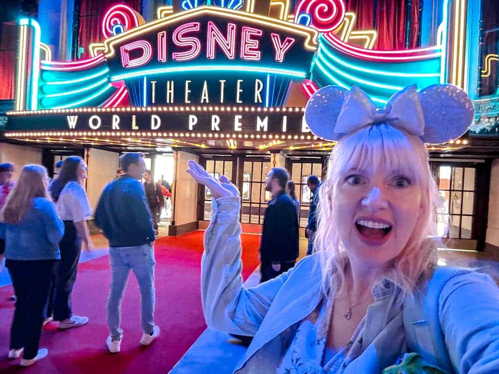 Carrie-Anne in sparkly ears smiling in front of the neon Disney Theater sign at World Premiere Disneyland Paris on opening day.