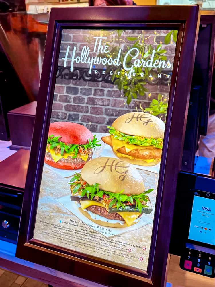 Digital screen showing burger options at Hollywood Gardens Restaurant in World Premiere Disneyland Paris, including vegan and signature choices.