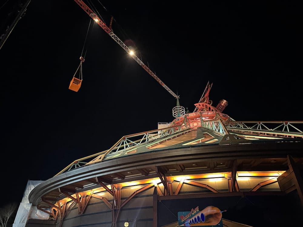 Nighttime view of Hyperspace Mountain at Disneyland Paris under construction with a crane and new lighting updates visible on the roof.