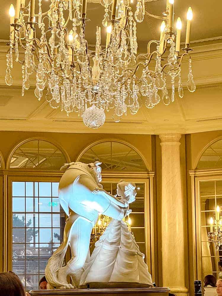 White sculpture of Belle and Beast dancing beneath a chandelier at La Table de Lumière in Disneyland Paris.
