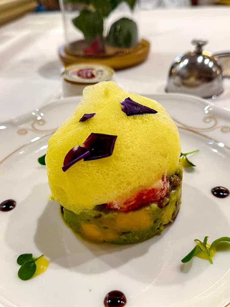 Close-up of the lobster and mango tartare starter topped with citrus foam and flower petals at La Table de Lumière, Disneyland Paris.